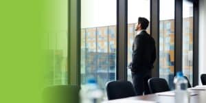 Businessman looking outside from glass wall in office