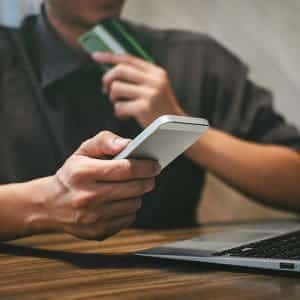 Close up view of a person's hands holding a phone and making a payment