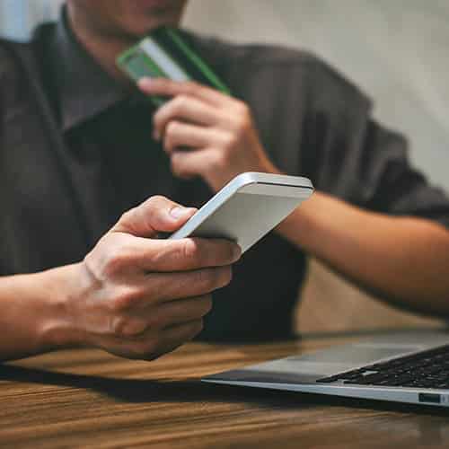 Close up view of a person's hands holding a phone and making a payment