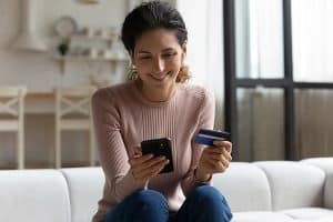 Happy female holding credit and phone