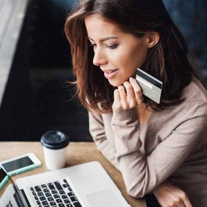 Female holding credit and using laptop