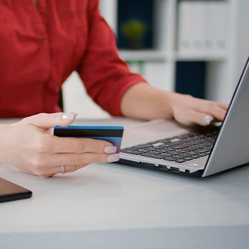 Close up view of human holding credit and using a laptop